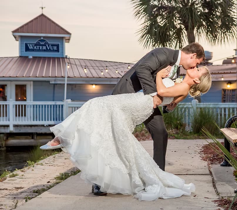 Couple sharing a kiss at an outdoor waterfront ceremony